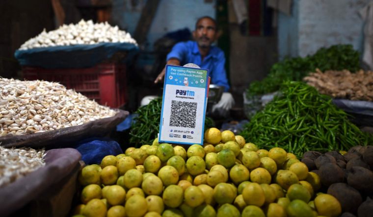 A vegetable vendor with a Paytm QR code on display at a stall waits for customers at a market in New Delhi